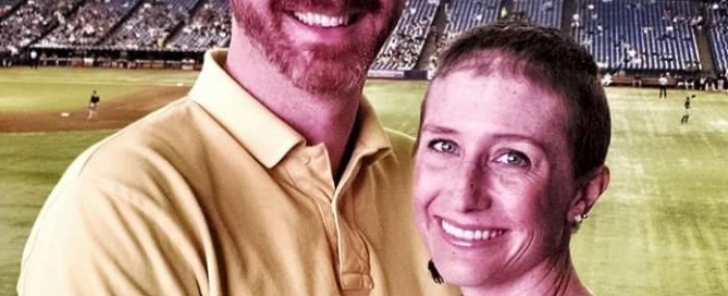 A man and woman posing for a photo at a baseball stadium.