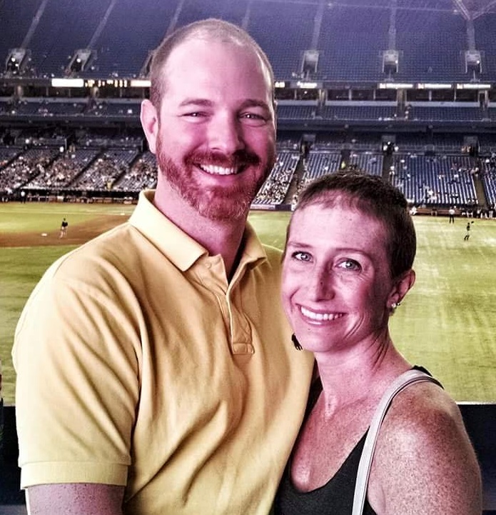 A man and woman posing for a photo at a baseball stadium.