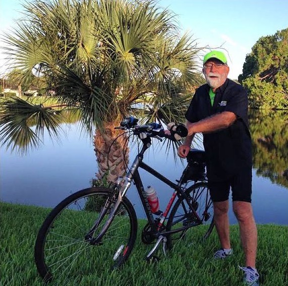 A man standing next to a bike next to a pond.